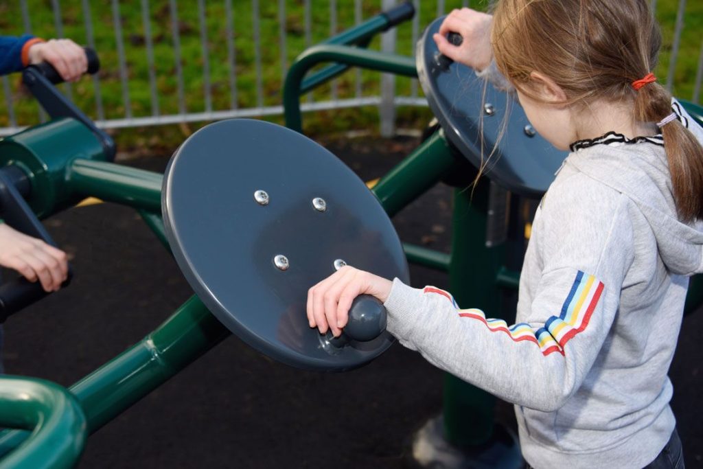 Children using tai chi disks in combined outdoor fitness gym