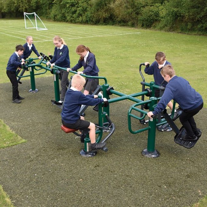 A group of children using different parts of a multi-gym outdoor exercise set