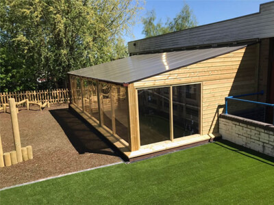 Wooden outdoor classroom adjoining school building with slanted roof and large windows
