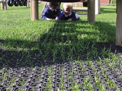 Rubber protective grass mats used under a piece of playground equipment to promote playground health and safety