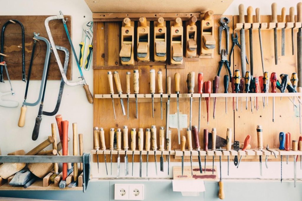 The wall of a tool shed with many different wooden tools mounted on the wall