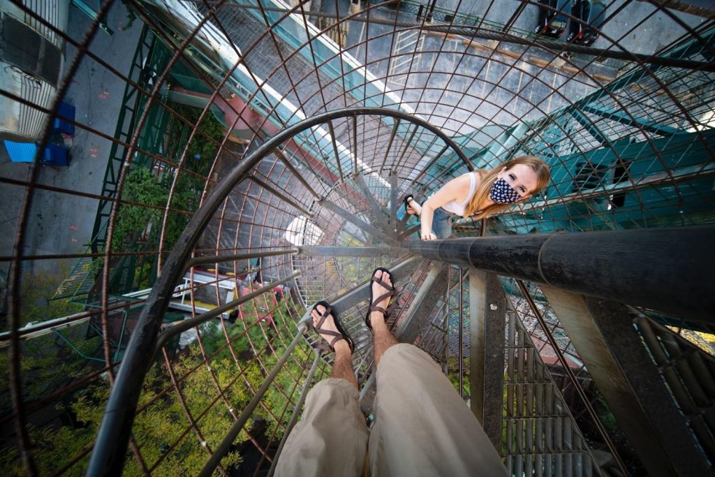 A downward view of a metal spiral staircase above a green area