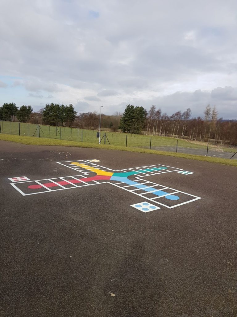 Our colourful playground markings design- the giant Ludo Board Game. Four players  given the colours yellow, green, blue and red roll dice to work their way towards the centre to win the game.
