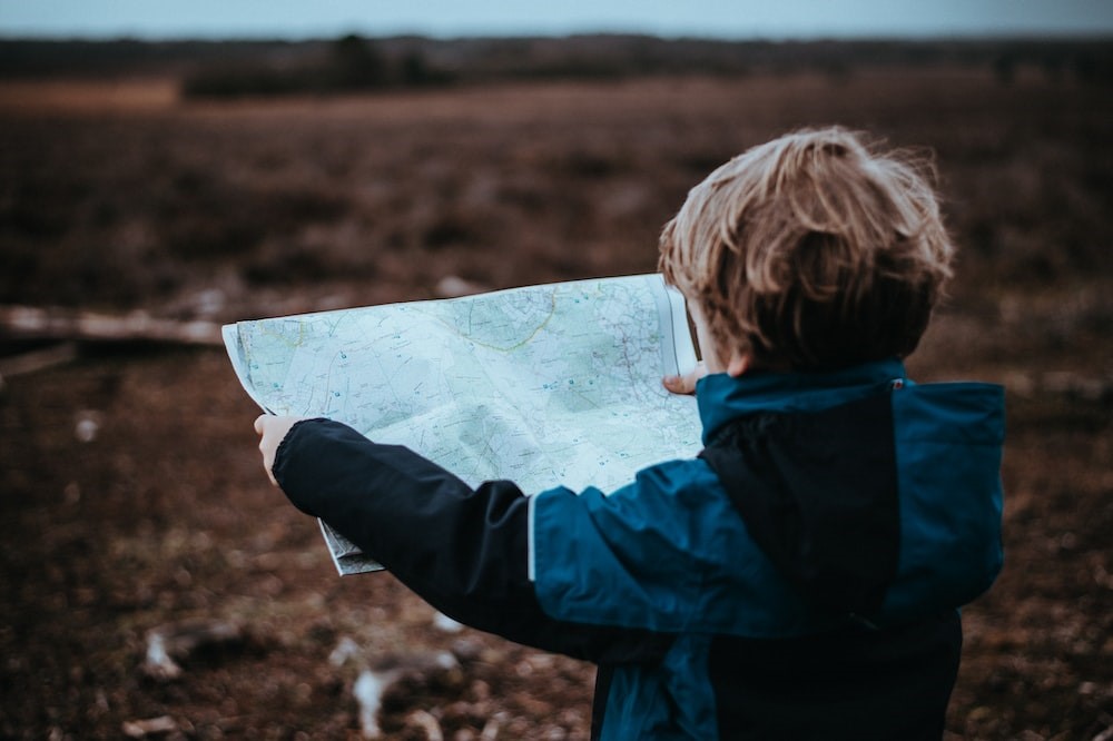 A young child outdoors looking at a map