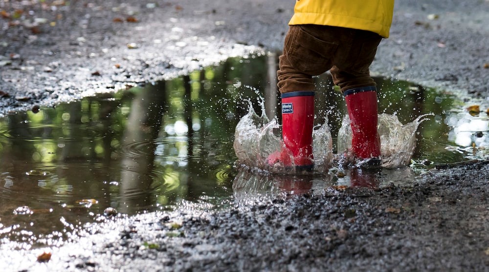 child splashing in muddy puddle