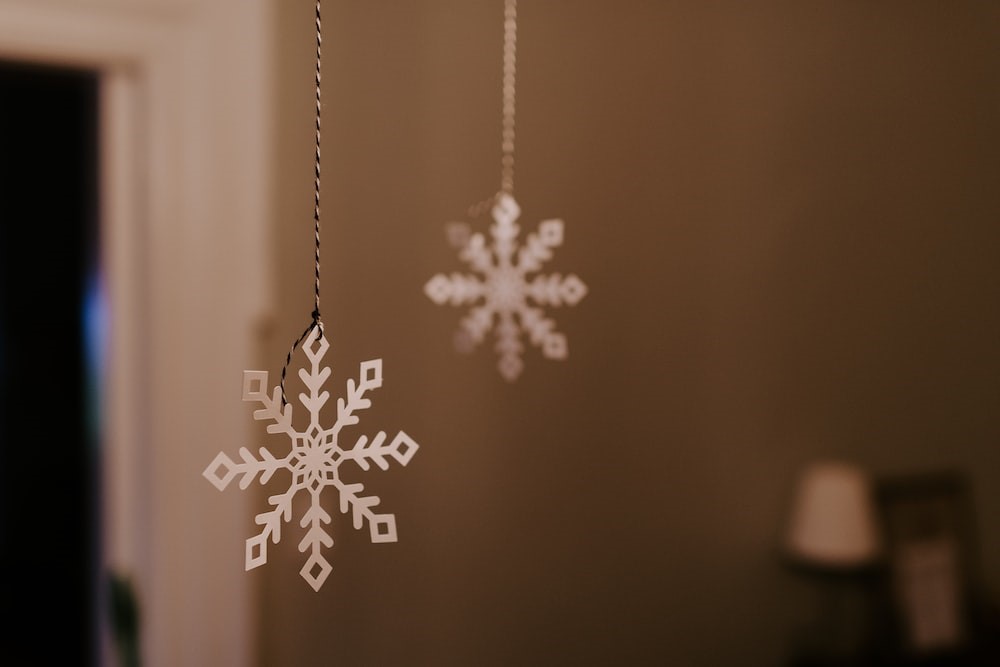 Two white paper snowflakes hanging from string from a ceiling.