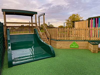 Giant bespoke playground structure in Nottinghamshire School Playground with wide low green slide and timber walkways and playground fencing