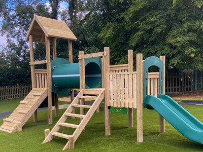 Timber play structure with play tower, slide, climbing slope and tunnel