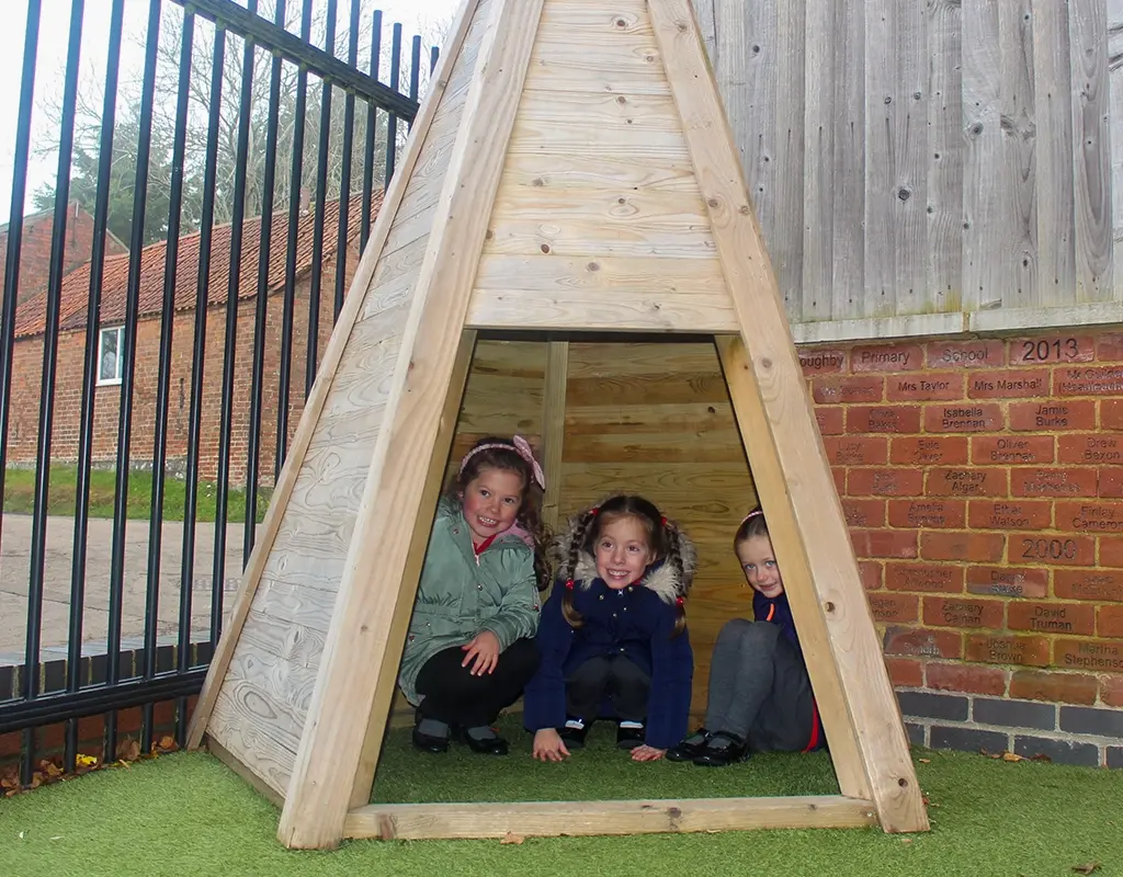 Children in a small wooden tee-pee structure in a Nottinghamshire school playground