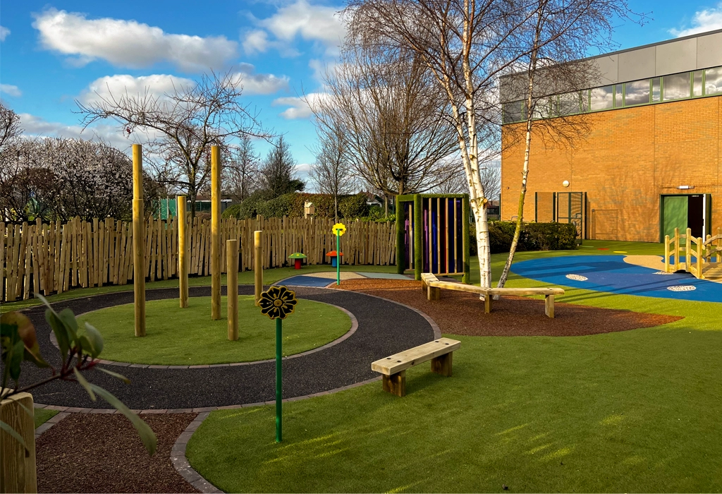 School playground with rubber flooring, wooden agility sticks, and wooden benches