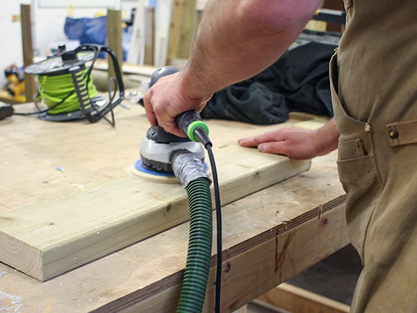 sanding wooden beam for our playground equipment in the workshop