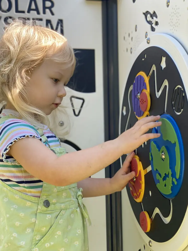 child playing with tactile rotating space themed panel