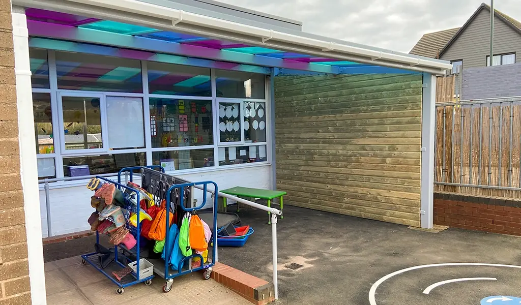 Outdoor perspex shelter canopy with book bag trollies for playground storage