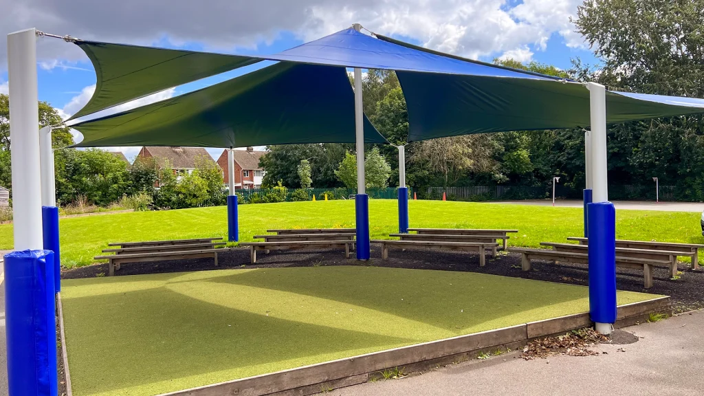 Large outdoor open classroom space with 4 combined blue, triangular sail shades