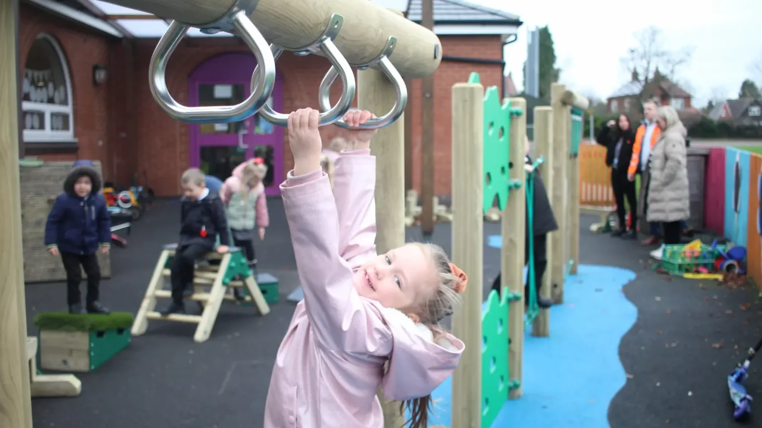 EYFS Child dangling from the climbing elements of their trim trail