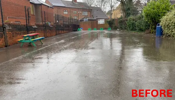 school playground before refurbishment showing wet, worn tarmac surfacing
