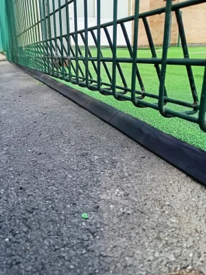 neat rubber safety surfacing edging against tarmac and fencing