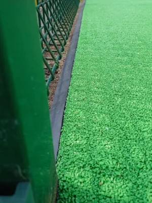 smooth rubber edging seam next to green rubber mulch surfacing