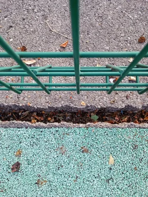 cracked playground edging with weeds growing through the gap