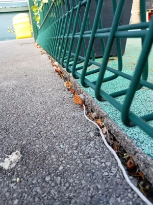 gap in poor quality playground edging with leaves and debris