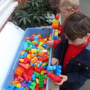 Children playing with sensory blocks on a wooden outdoor side table in a Nottinghamshire school playground