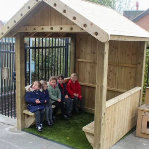 children inside a mini square wooden reading huts for schools with artificial grass interior and benches in a Nottinghamshire school playground