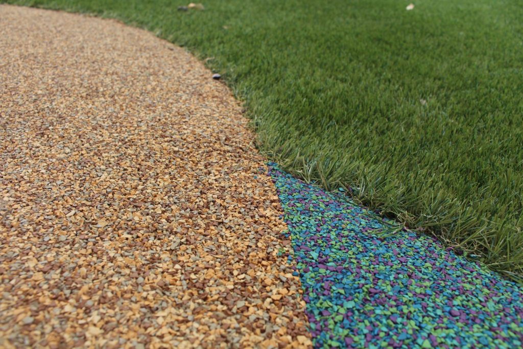 Colourful rubber mulch pathway with adjoining artificial grass