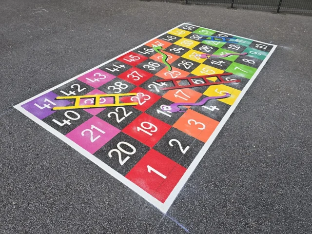 1-50 snakes and ladders grid playground markings with rainbow colours for primary school children